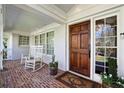 Cozy front porch with brick floor, white rocking chairs, and classic wood door at 1299 W Wesley Nw Rd, Atlanta, GA 30327