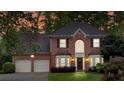 Charming two-story red brick home with an attached two-car garage beautifully illuminated at twilight at 3951 Lorien Nw Way, Kennesaw, GA 30152