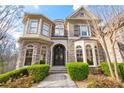 Stunning stone front facade featuring an arched entryway, custom iron door, and manicured landscaping at 8069 Kenstone Ct, Sandy Springs, GA 30350