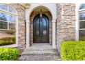 Close up of front door entrance with stone and black metal design and manicured bushes at 8069 Kenstone Ct, Sandy Springs, GA 30350