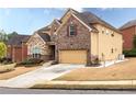 A two-story home featuring a stone and brick facade, manicured landscaping, and an attached garage at 5877 Stow Dr, Tucker, GA 30084