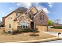 Side view of a two-story home featuring mixed siding, manicured landscaping, and an attached garage at 5877 Stow Dr, Tucker, GA 30084