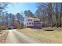 Scenic view of a home with a long driveway and large front yard, set amongst mature trees at 165 Carriage Gate Dr, Sharpsburg, GA 30277