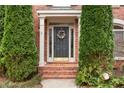 Close-up of a home's entrance with a decorated front door and manicured evergreens at 2611 Winterthur Main Nw, Kennesaw, GA 30144