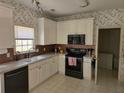 Well-lit kitchen featuring white cabinetry, modern appliances, and unique floral wallpaper at 275 Rose Ivy Ct, Lawrenceville, GA 30043