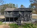 Image shows the rear exterior of the home with a dark siding and elevated outdoor deck with stairs at 3427 Saddleton Way, Douglasville, GA 30134