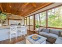 Inviting screened-in porch with a full outdoor kitchen, comfortable seating, and a cozy gas fireplace at 551 Rokeby Dr, Woodstock, GA 30188