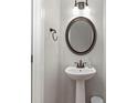 A convenient half bathroom featuring a pedestal sink, round mirror, and neutral wall color at 1570 Lenox Overlook Ne Rd, Atlanta, GA 30329