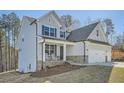 Side view of a gray two-story home with stone accents, three car garage, a porch with rocking chairs, and landscaped yard at 115 Laurelwood Ln, Dallas, GA 30157