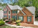 Elegant brick home with lush landscaping, flowering shrubs, and blue-green shutters at 535 Woodbrook Way, Lawrenceville, GA 30043