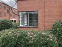 Building exterior with a large, modern window surrounded by symmetrical greenery and a matching brick facade at 1148 Briarcliff Ne Rd # 1, Atlanta, GA 30306
