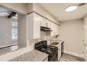 Bright kitchen featuring granite countertops, white cabinets, and black appliances at 3111 Fairington Dr, Lithonia, GA 30038