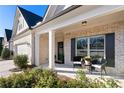 Charming covered front porch with seating, decorative brickwork and a welcoming entry at 130 Brayden Park Dr, Canton, GA 30115