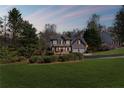 Dusk view of a charming two-story home with a well-manicured lawn, two-car garage and inviting front porch at 5635 Charleston Bay Dr, Cumming, GA 30041