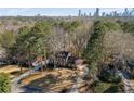 Aerial shot of a suburban home surrounded by mature trees with city skyline in the distance at 725 Glengary Ne Way, Atlanta, GA 30342