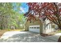 Side view of a charming home featuring an attached garage, a well-maintained driveway, and a beautifully landscaped yard at 195 Creekside Way, Mcdonough, GA 30252