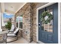 Inviting front porch features stone accents, rocking chairs, and a stylish blue front door with a wreath at 708 Chipping Sparrow St, Canton, GA 30115