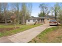 Cozy house with a lengthy driveway, stone accents, a lush lawn, and a newly planted tree at 1752 Atherton Dr, Decatur, GA 30035