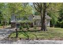 Charming split-level home featuring stone accents, a well-maintained lawn, and a mature shade tree at 8876 Ashwood Dr, Riverdale, GA 30274