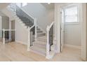 Elegant staircase with white railings, black wrought iron spindles, and light hardwood floors at 5210 Davenport Pl, Roswell, GA 30075