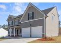 Beautiful house with gray siding, white garage doors, and a well-maintained lawn, set against a bright sky at 469 Ralph Still Rd, Dacula, GA 30019
