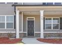 Inviting front entrance with gray door, white columns, brick accents, and neatly landscaped flower beds at 469 Ralph Still Rd, Dacula, GA 30019