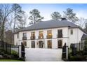 Stately two-story home featuring a gated entrance and a circular driveway, surrounded by mature trees at 5245 Kenbrook Way, Sandy Springs, GA 30327