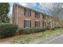 Side view of brick townhouse with black shutters, well maintained landscaping, and green lawn at 6700 Roswell Rd # 14C, Atlanta, GA 30328