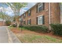 Side view of brick townhouse with black shutters, well maintained landscaping, and green lawn at 6700 Roswell Rd # 14C, Atlanta, GA 30328