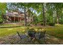 Secluded backyard with a stone patio and firepit for outdoor entertainment, surrounded by lush greenery and trees at 275 Tynebrae Pl, Roswell, GA 30075