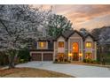 Charming home with a two-car garage, a brick-accented driveway, and mature landscaping under a beautiful evening sky at 275 Tynebrae Pl, Roswell, GA 30075