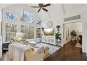 Bright and airy living room featuring vaulted ceiling, large windows with wooded views, hardwood floors, and stylish decor at 1270 Smokehouse Trl, Cumming, GA 30041