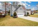 Side view of home, showing well-maintained lawn, two-car garage, and mature trees at 4015 Embassy Way, Lilburn, GA 30047