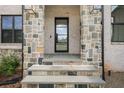 Stylish front entryway features stone accents, a modern glass door, and bluestone steps at 4980 Wildeoak Trl, Douglasville, GA 30135