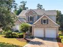 Charming two-story home with brick accents, lush landscaping, and a practical two-car garage at 152 Vinings Lake Ct, Mableton, GA 30126