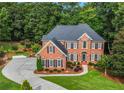 Beautiful aerial view of a brick home with a long driveway and mature trees in a serene setting at 2930 Monticello Dr, Cumming, GA 30041