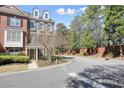 Brick townhome showcasing manicured landscaping, walkway, and access road, under a partly cloudy sky, complemented by mature trees at 4406 Kendall Way, Roswell, GA 30075