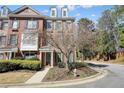 Brick townhome featuring manicured landscaping, a charming entrance, all under a bright, partly cloudy sky at 4406 Kendall Way, Roswell, GA 30075