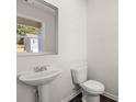Well-lit powder room with pedestal sink and modern toilet at 8229 Coldstream Dr, Fairburn, GA 30213