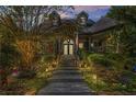 Evening shot of a charming home with stone stairway, manicured landscaping, and illuminated exterior lights at 90 W Peachtree St, Norcross, GA 30071