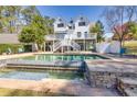 Gorgeous in-ground pool with an attached waterfall feature, surrounded by patio furniture at 1768 Hood Rd, Dacula, GA 30019