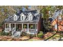Charming brick home featuring dormer windows, covered front porch, and mature trees at 121 Rising Star Rd, Fayetteville, GA 30215