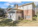Back exterior view showcasing a sunroom, brick facade, and a spacious yard at 5269 Wyntercreek Dr, Atlanta, GA 30338