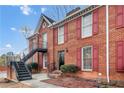 Exterior view of two-story brick home with red shutters and a black stairway leading to an upper unit at 1166 Booth Sw Rd # 605, Marietta, GA 30008
