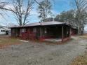 Side view of house with shingle siding, red trim, carport, and gravel driveway at 3844 Oglesby Rd, Powder Springs, GA 30127