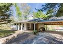 Side view of home featuring covered parking and a covered porch with outdoor seating, surrounded by mature trees at 5369 Blue Grass Ln, Sugar Hill, GA 30518