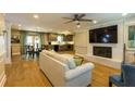 Open concept living area with hardwood floors, a fireplace, modern lighting, and a view of the kitchen and dining area at 5369 Blue Grass Ln, Sugar Hill, GA 30518