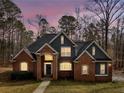 This elegant brick home showcases exterior illumination highlighting architectural details and its well-manicured landscape at 355 Parker Rd, Covington, GA 30014