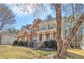 Two-story brick home featuring a covered front porch, mature trees, and an inviting curb appeal at 4630 Smokestone Dr, Douglasville, GA 30135