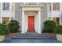 Close up view of a home's entrance with white pillars, a red front door, and manicured landscaping at 2820 Andrews Nw Dr, Atlanta, GA 30305